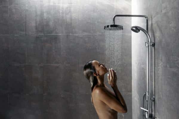 Mujer usando una ducha con dos tipos de grifos.